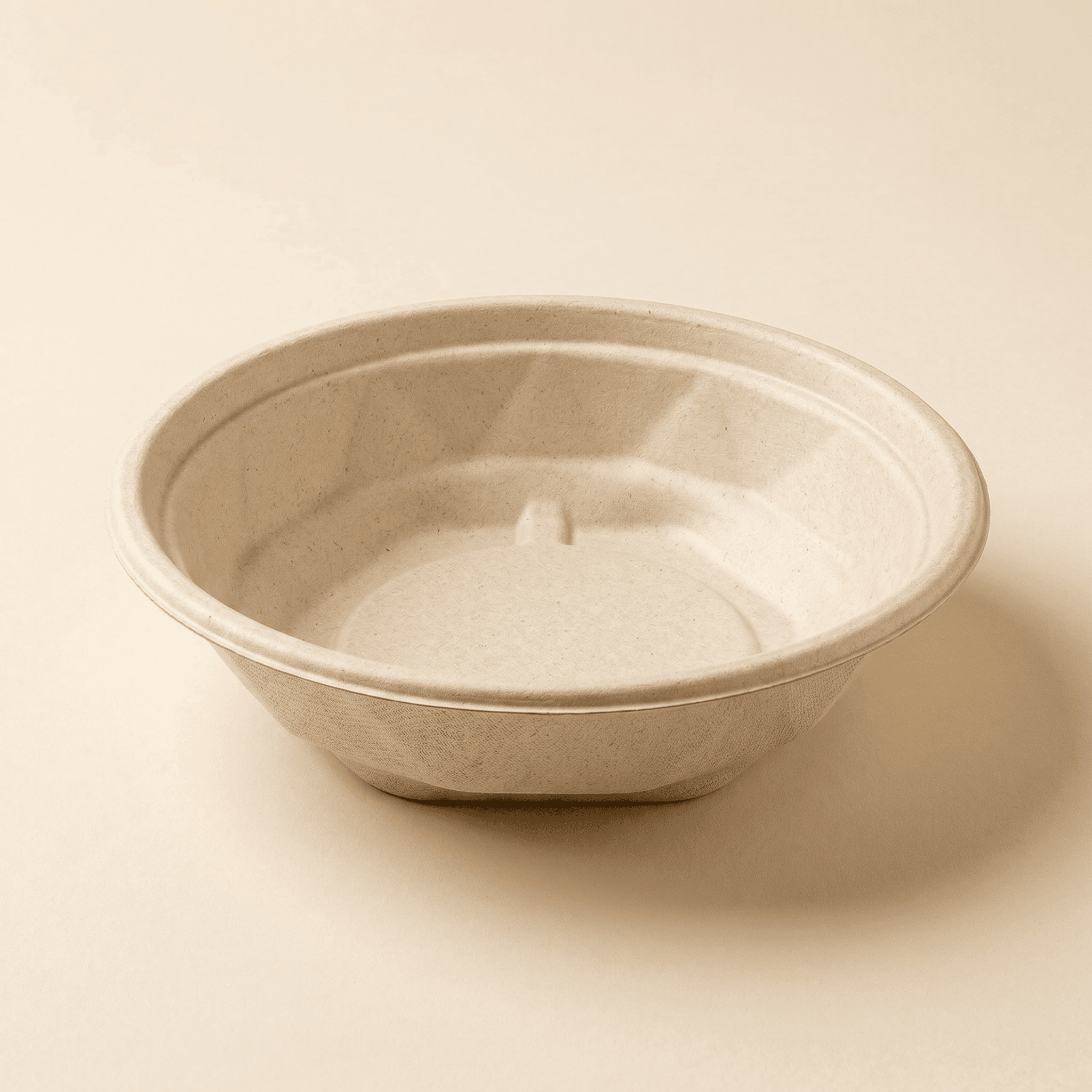 16 oz round bagasse bowl at a three-quarter angle on a cream studio background, showing the wide rolled rim and the faceted molded sugarcane fiber sidewall