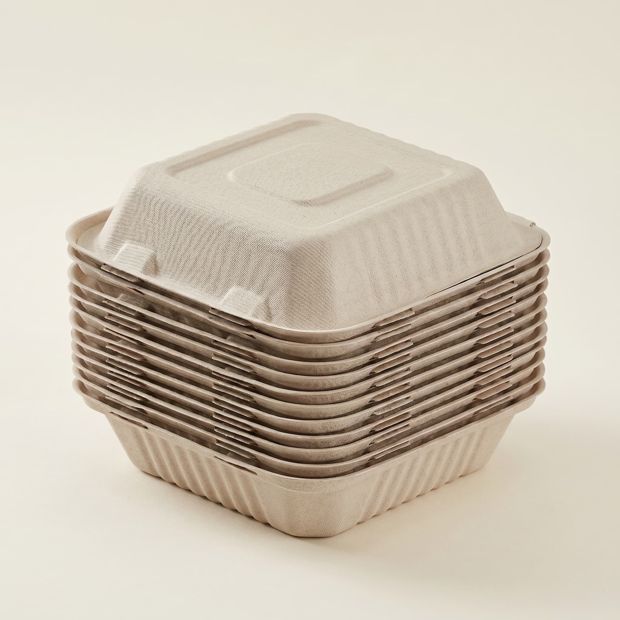A stack of closed 8×8 bagasse clamshells showing how compactly they nest for storage