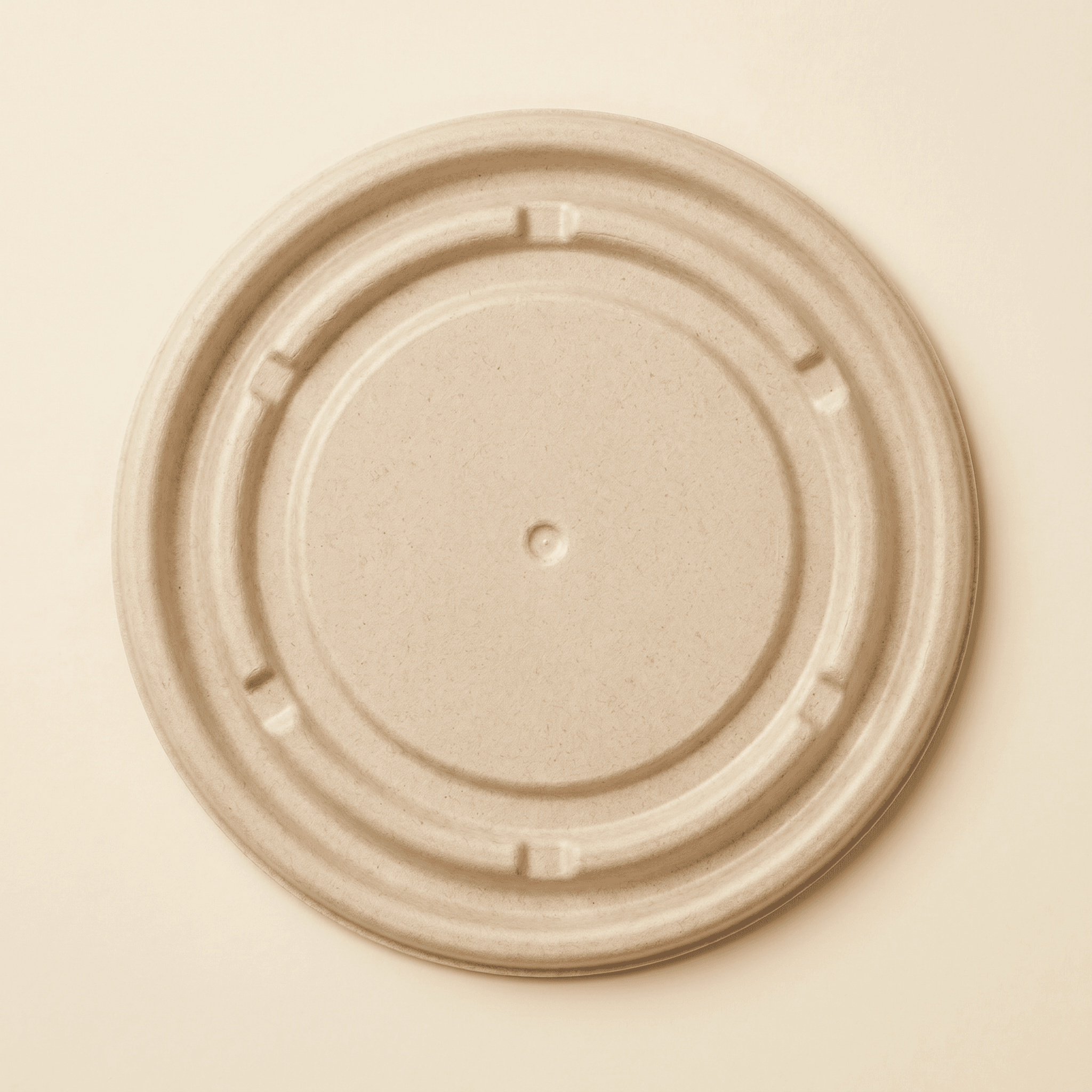 Top-down view of the bagasse fiber lid showing the raised central panel, concentric stepped grooves, center dimple and small tab indents