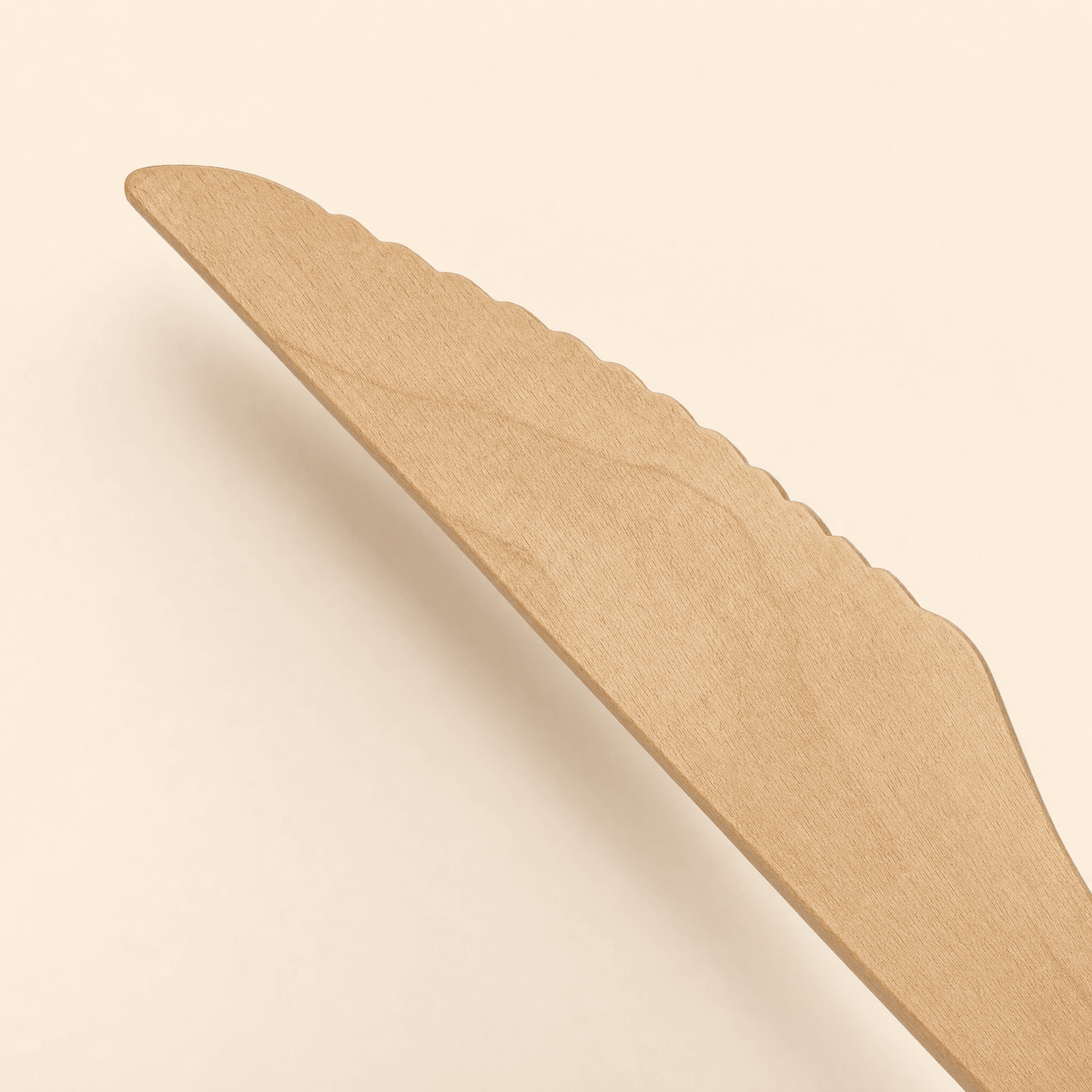 Close-up of the knife's serrated, scalloped cutting edge and the natural birch wood grain